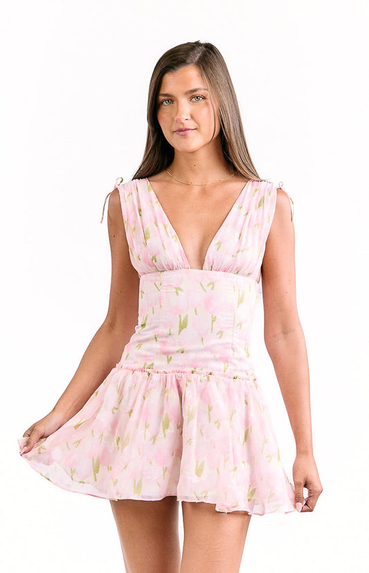 Front view of a pink floral mini dress with a deep V-neck, tie-shoulder straps, and a ruffled hem