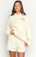 girl wearing a cream coloured hoodie with an emboidered red gingham cowboy boot and navy star on the back