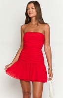 a brunette model wears a red strapless mini dress and gold pendant necklace with a seashell design