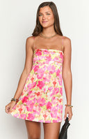 Fashion model showcasing a beautiful pink and yellow floral print mini slip dress, featuring delicate spaghetti straps and a flowing A-line silhouette, ideal for warm weather.
