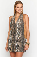 blonde model wearing a leopard print denim mini dress with a halter neck tie and button down front