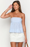 Girl wearing blue strapless top and white mini skirt holding cocktail drink in front of glass door.