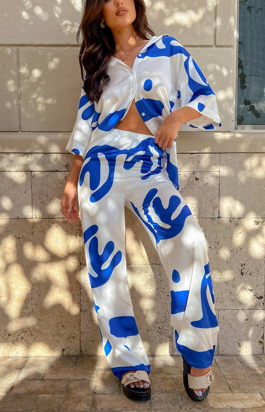 Satin wide leg pants with white and royal blue abstract pattern on brunette model. 