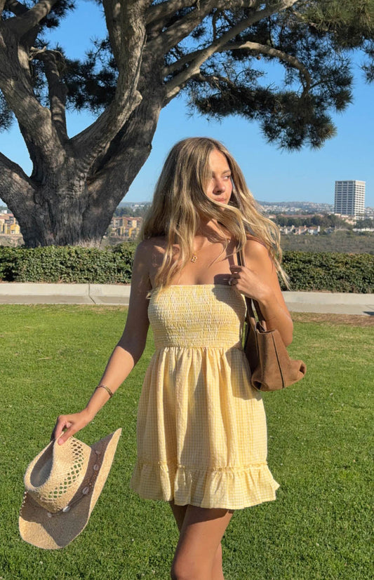 model wearing a strapless yellow mini dress with ruffle details