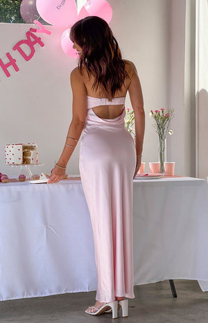 Back of girl wearing light pink maxi dress and white strappy heels.