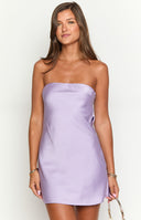 a girl wears a lilac mini dress and pendant necklace while holding a rhinestone bag 