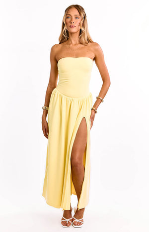 A model wears a yellow strapless formal maxi dress. This elegant gown features a straight neckline and a gathered waist detail for a flattering silhouette. A sophisticated choice for a wedding guest or prom.