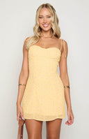 blonde model wearing baby yellow mini dress with purple flower details with bust cup detail and tie straps
