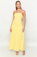Girl looking back in a yellow strapless maxi dress and silver cowboy boots.