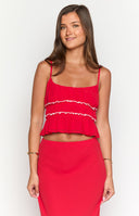 Brunette model wearing a red crop top with contrast white details styled with a matching red maxi skirt and gold jewellery.