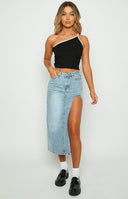 Brunette Model is posed in a blue denim midi skirt. The midi skirt features a cutout/leg split on the left side.
